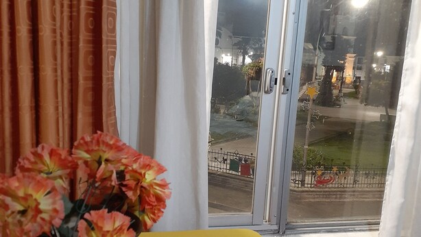 A room with a yellow table, a green vase with flowers, and a window with curtains. - HOTEL CENTRAL (Latacunga)