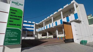 Un edificio con un cartel que enumera los servicios, entre ellos habitaciones, una sala de reuniones, un restaurante y un área de estacionamiento.