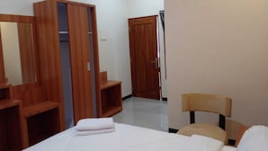 Una habitación de hotel con una cama, un armario de madera, una silla y una puerta que da a otra habitación.
