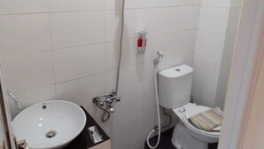 Un baño pequeño con lavamanos blanco, inodoro y ducha.