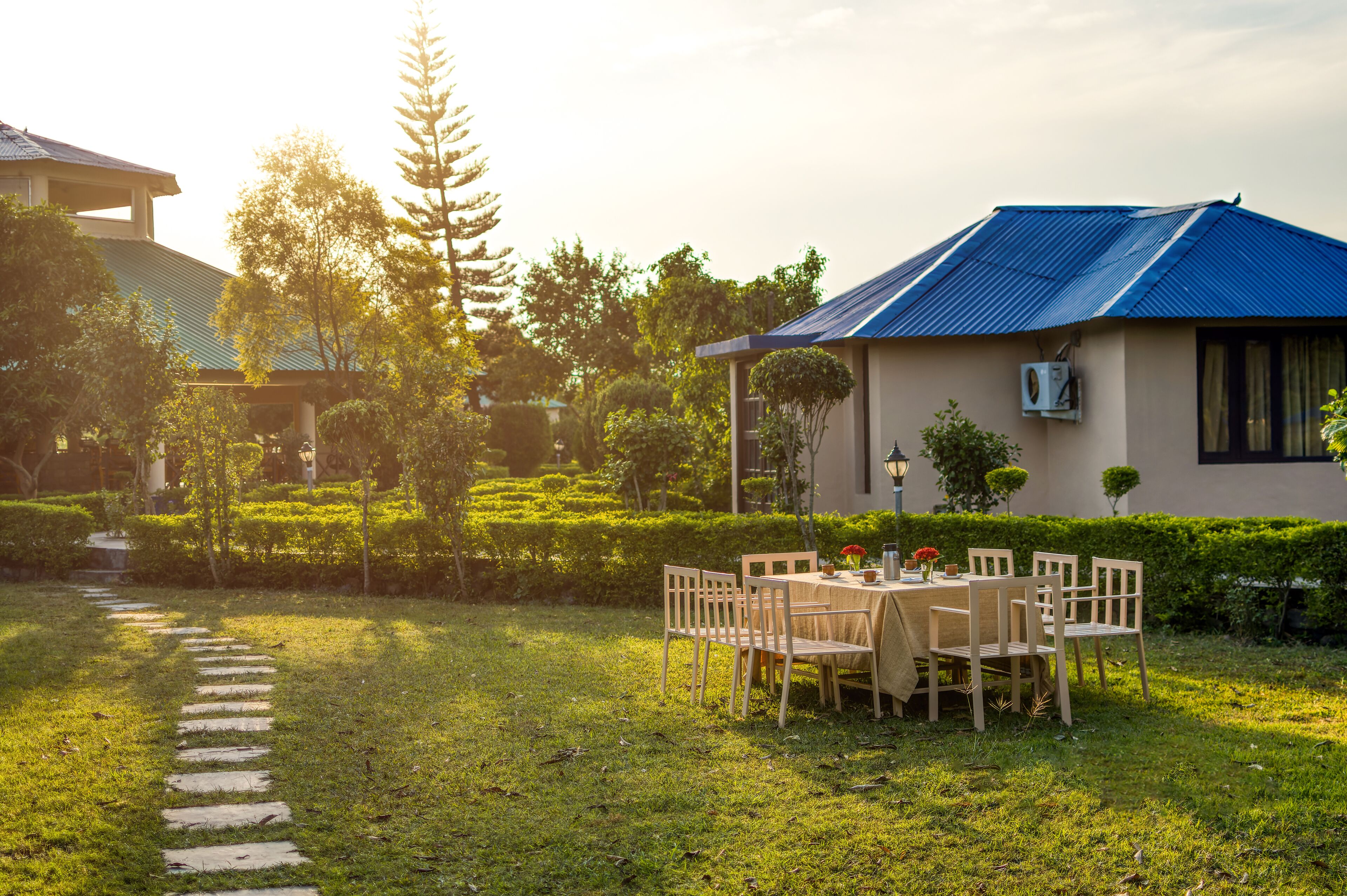 A well-maintained outdoor dining area with a table and chairs, surrounded by lush greenery and a clear pathway.