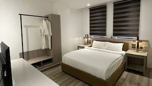 A modern bedroom with a large bed, bedside tables, a desk, and a wardrobe. - Asaricha Tropical Beach Resort (Pasuquin)