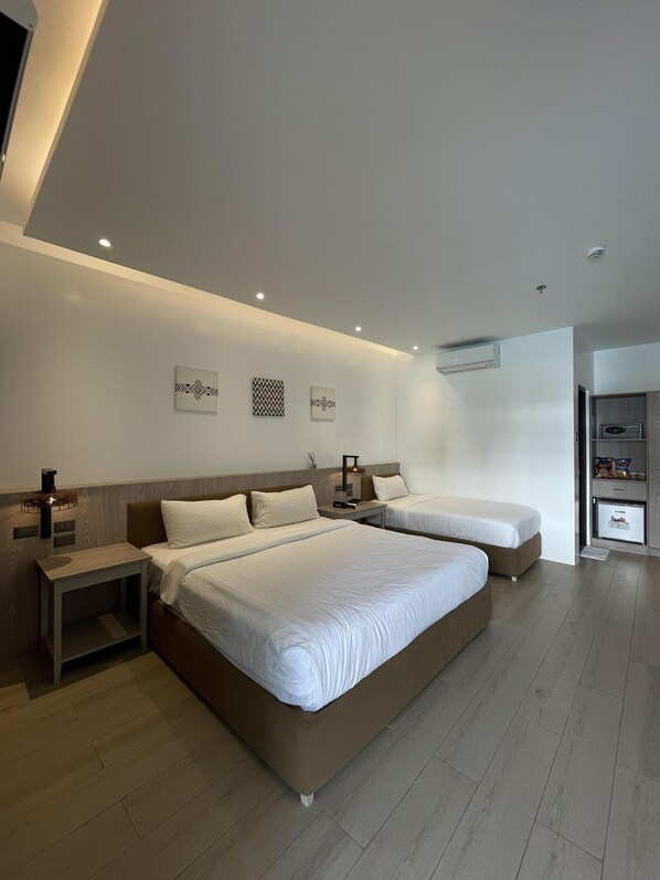 A modern hotel room with two beds, a bedside table, a nightstand, and a built-in wardrobe.