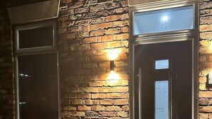 A brick exterior with a dark-colored door and a window. - Immaculate 4-Bed detached House in Bootle (Bootle)