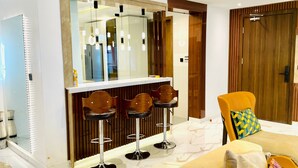 Un salon moderne avec un canapé, une porte en bois et un coin bar équipé de tabourets.
