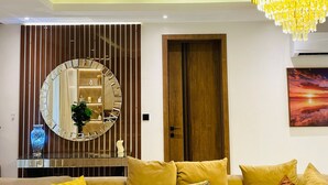 Un salon moderne avec un miroir rond, une porte en bois, un lustre et un tableau accroché au mur.