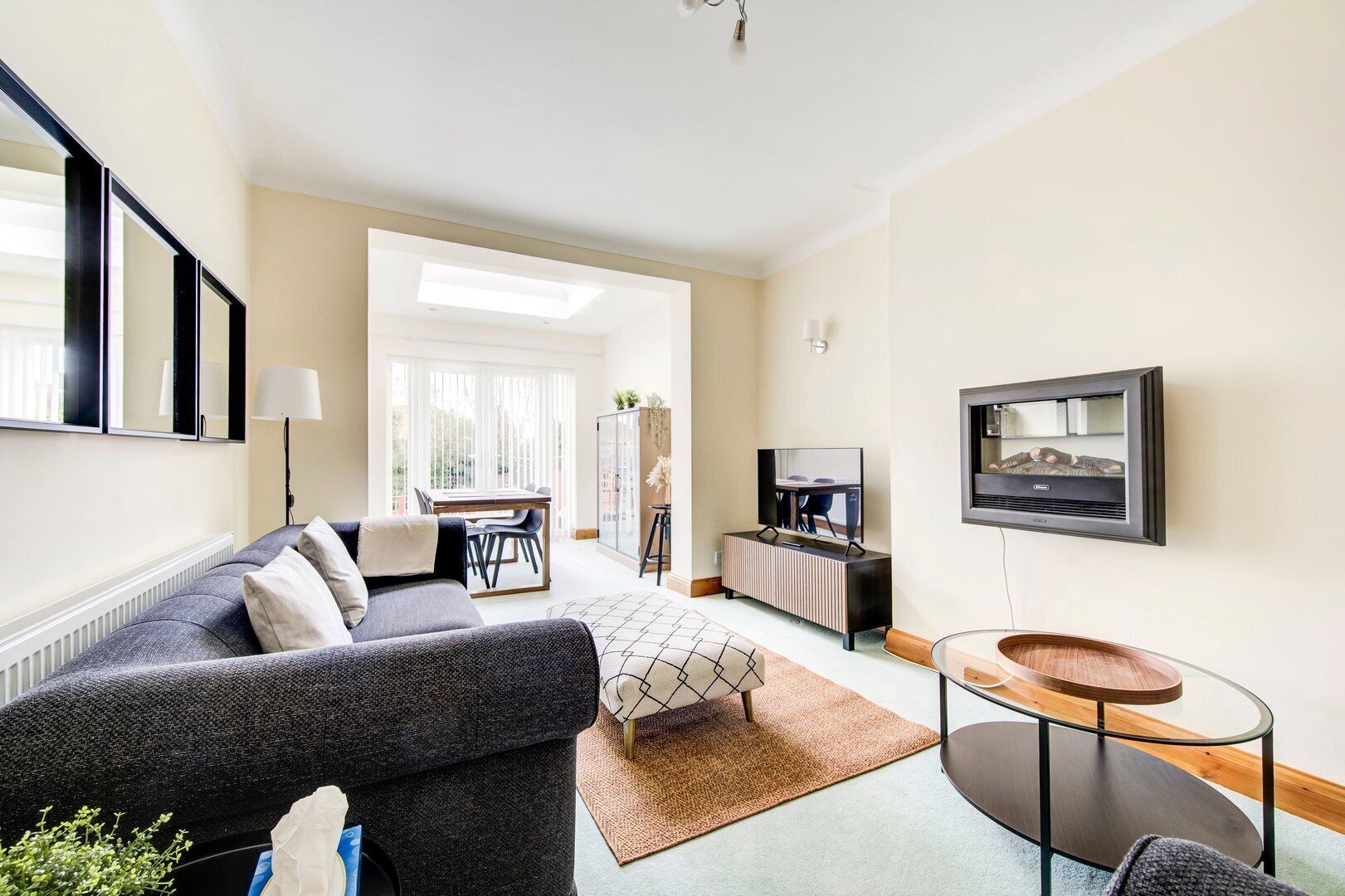Ein modernes Wohnzimmer mit Sofa, Couchtisch, Fernseher und einem Essbereich mit Tisch und Stühlen.