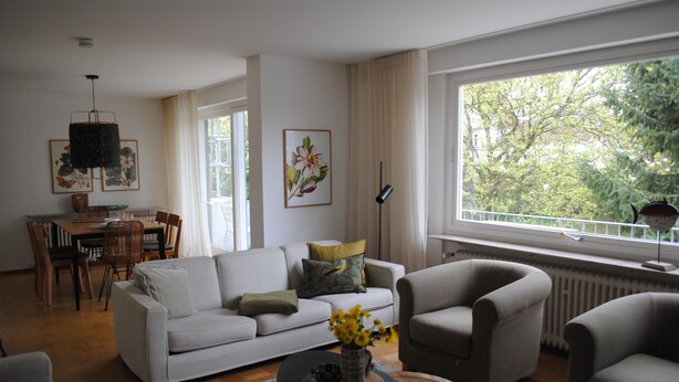 Una sala de estar con sofá, sillones, una mesa de centro y un comedor con sillas y una mesa.