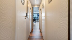 A hallway with doors, a wooden floor, and a view of the outside.