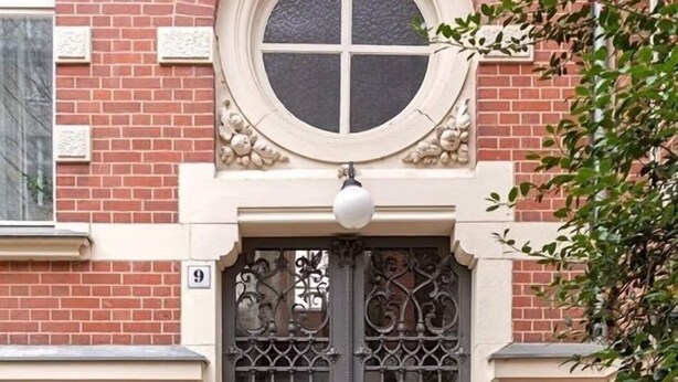 A building entrance with a double door, a round window above, and a brick facade.