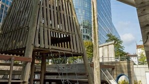 A wooden structure with a conical roof, a metal slide, and a staircase leading up to it.