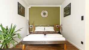 A bedroom with a bed, a green accent wall, and a clock.