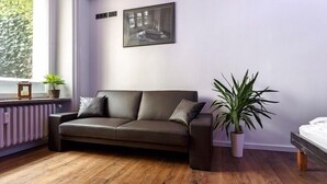 A modern living room with a dark brown leather sofa, a potted plant, and a framed picture on the wall.