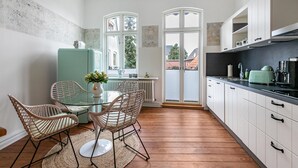 A modern kitchen with a dining area, white cabinetry, and a view through a large window. - Apartment 'Wohnoase Im Denkmal' with Private Terrace, Balcony and Wi-Fi (Garding Kirchspiel)