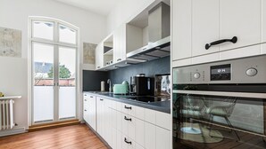 A modern kitchen with white cabinets, a black countertop, a Juno oven, and a view through a glass door. - Apartment 'Wohnoase Im Denkmal' with Private Terrace, Balcony and Wi-Fi (Garding Kirchspiel)