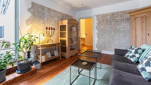 A living room with a wooden cabinet, a sofa, a small table, and a potted plant. - Apartment 'Wohnoase Im Denkmal' with Private Terrace, Balcony and Wi-Fi (Garding Kirchspiel)