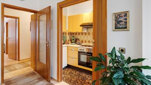 A compact kitchen with wooden cabinetry, a stove, and a tiled backsplash. - Apartment "Eva Maria" with Balcony and Wi-Fi (Pforzheim)