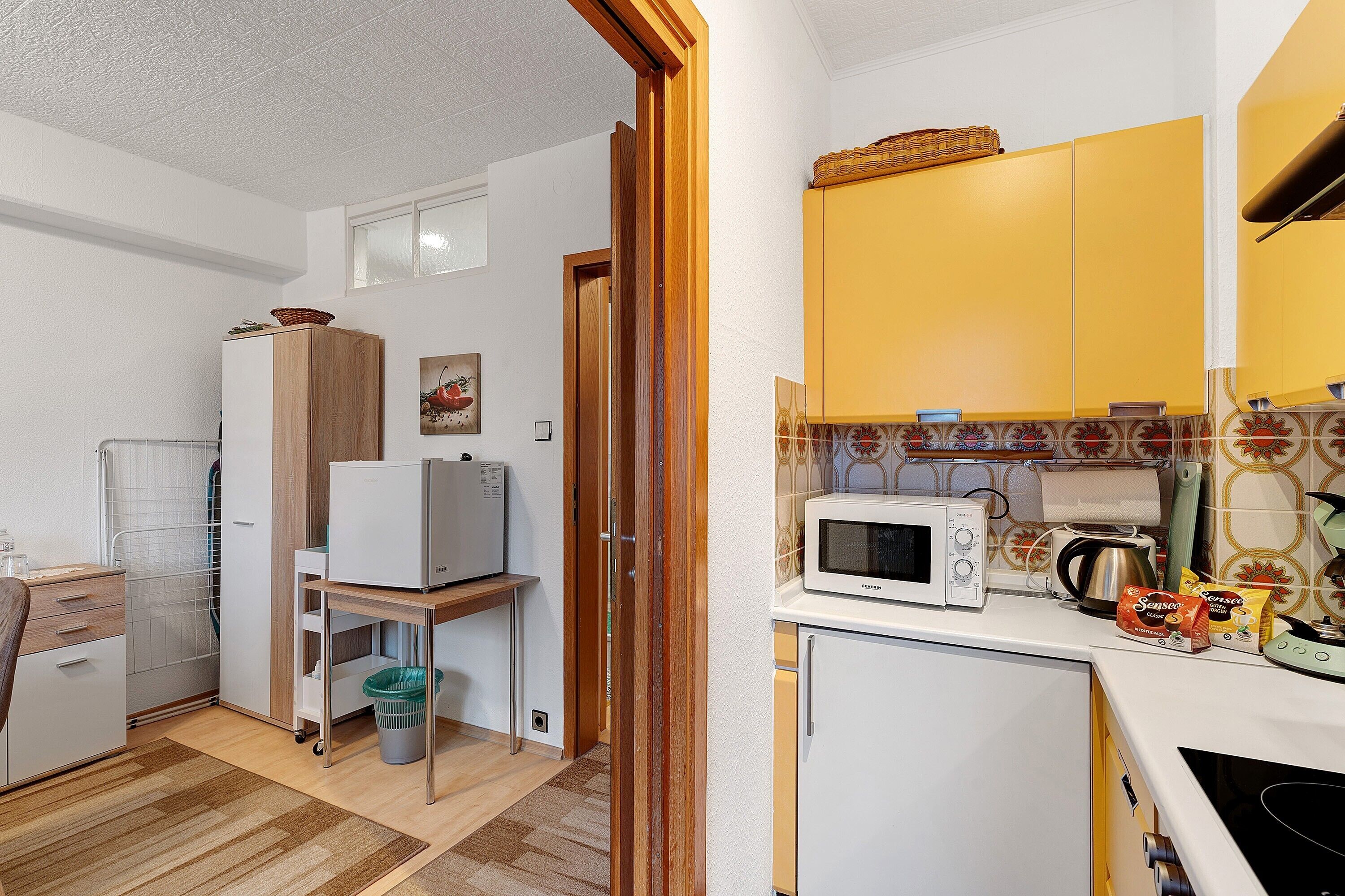 Una cocina compacta con microondas, tostadora y un refrigerador pequeño.