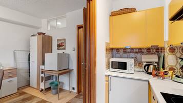 Una cocina compacta con microondas, tostadora y un refrigerador pequeño.