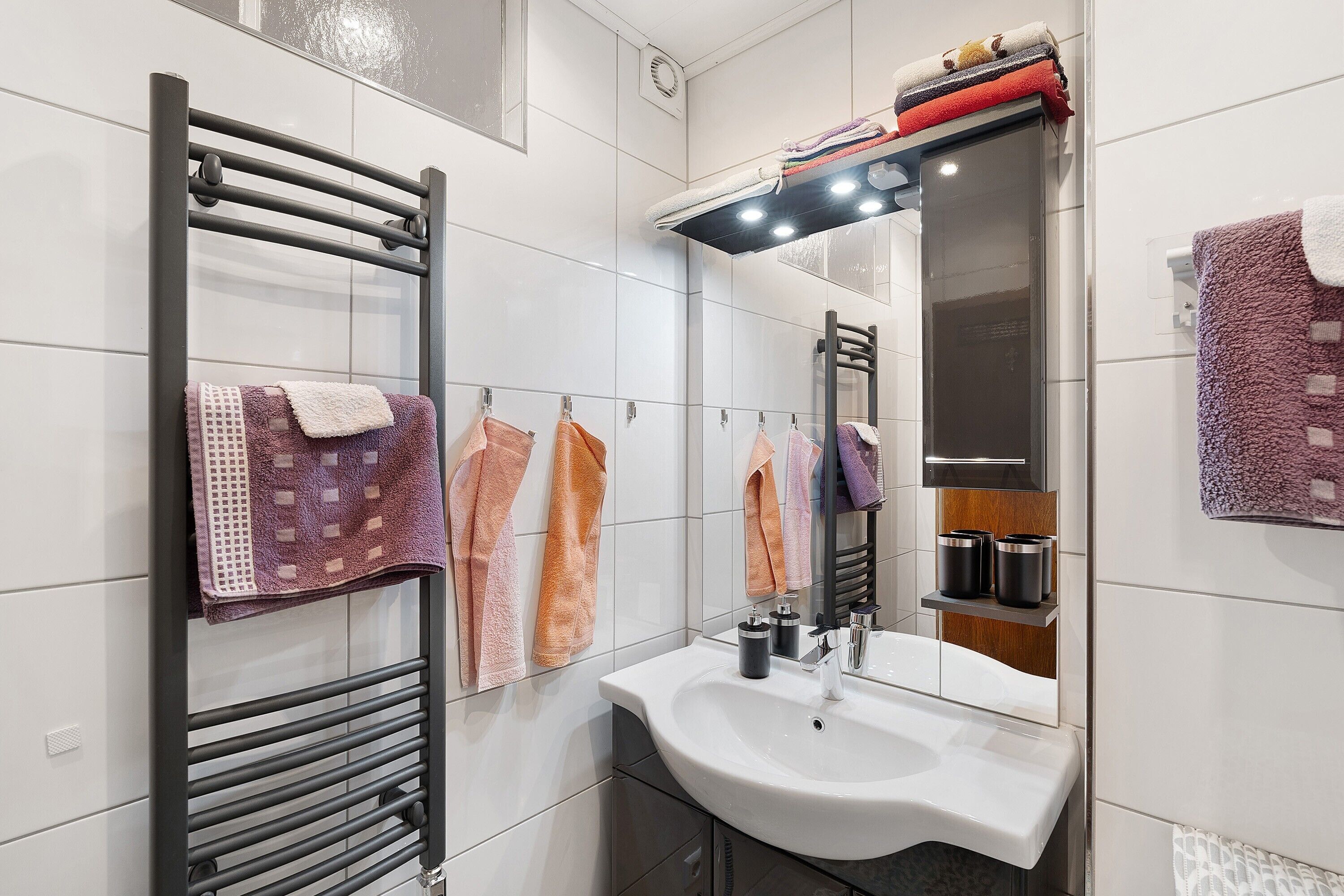 A modern bathroom with a built-in sink, a towel rack, and a mirror.