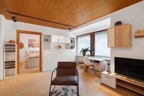 Un salon moderne avec un fauteuil marron, un téléviseur et un plafond en bois.