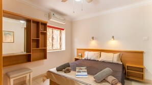 A neatly arranged bedroom with a bed, bedside tables, a bench, and a window with decorative bars. - Villa & Pool 3 Mellieħa Bay Retreat, Mellieha, Malta (Mellieha)