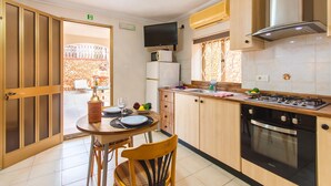 A modern kitchen with wooden cabinets, a built-in oven, a gas stove, and a flat-screen TV. - Villa & Pool 3 Mellieħa Bay Retreat, Mellieha, Malta (Mellieha)