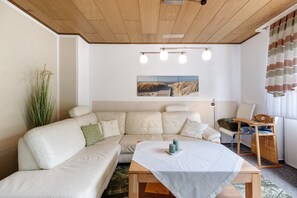Un salon moderne avec un canapé, une table basse, un tableau au mur et un plafond en bois.