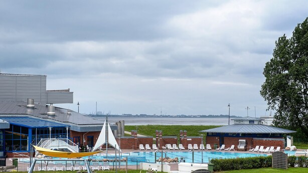 Ein Swimmingpool mit Liegestühlen, einer Hängematte und Blick auf das Meer.