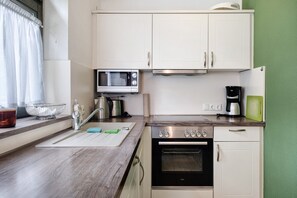 Une cuisine avec des meubles blancs, un four à micro-ondes, une cuisinière et une machine à café.