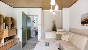 Ein modernes Wohnzimmer mit einer Couch, einem Couchtisch und einer grünen Tür, die in einen Küchenbereich führt.