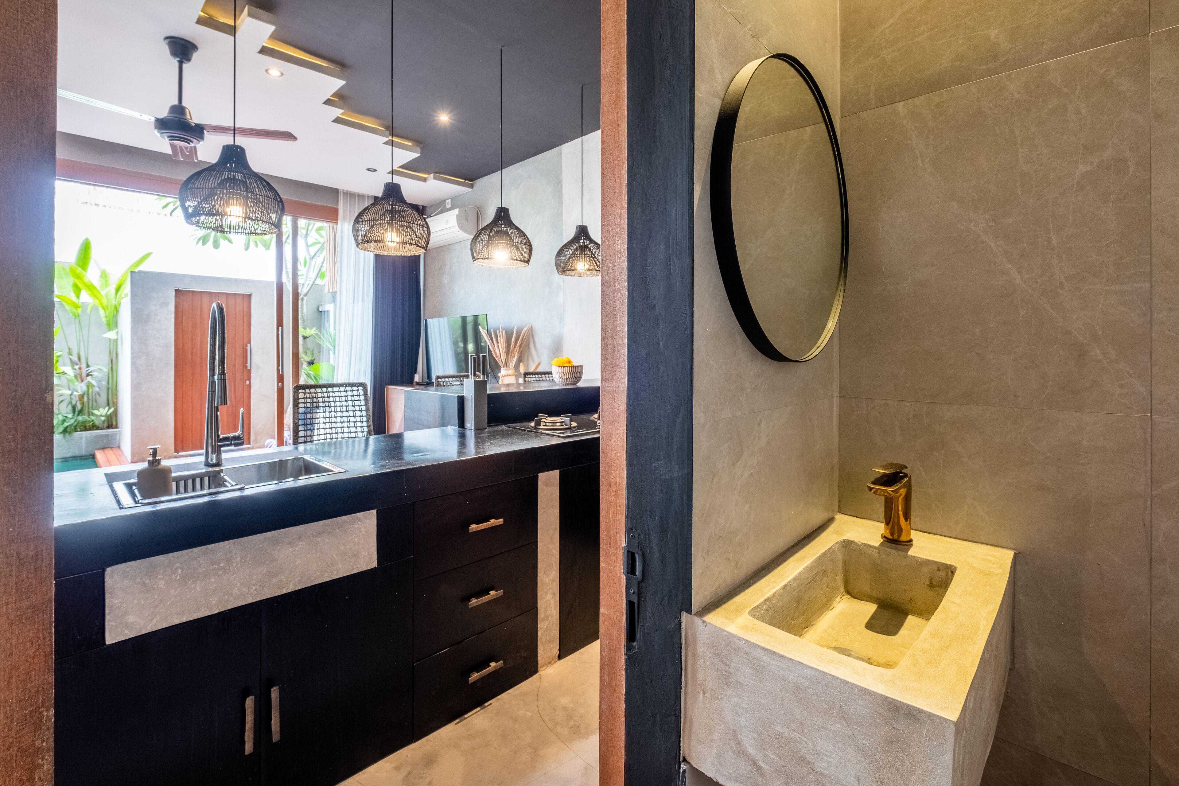 A modern kitchen with a black countertop, a sink, and pendant lights.