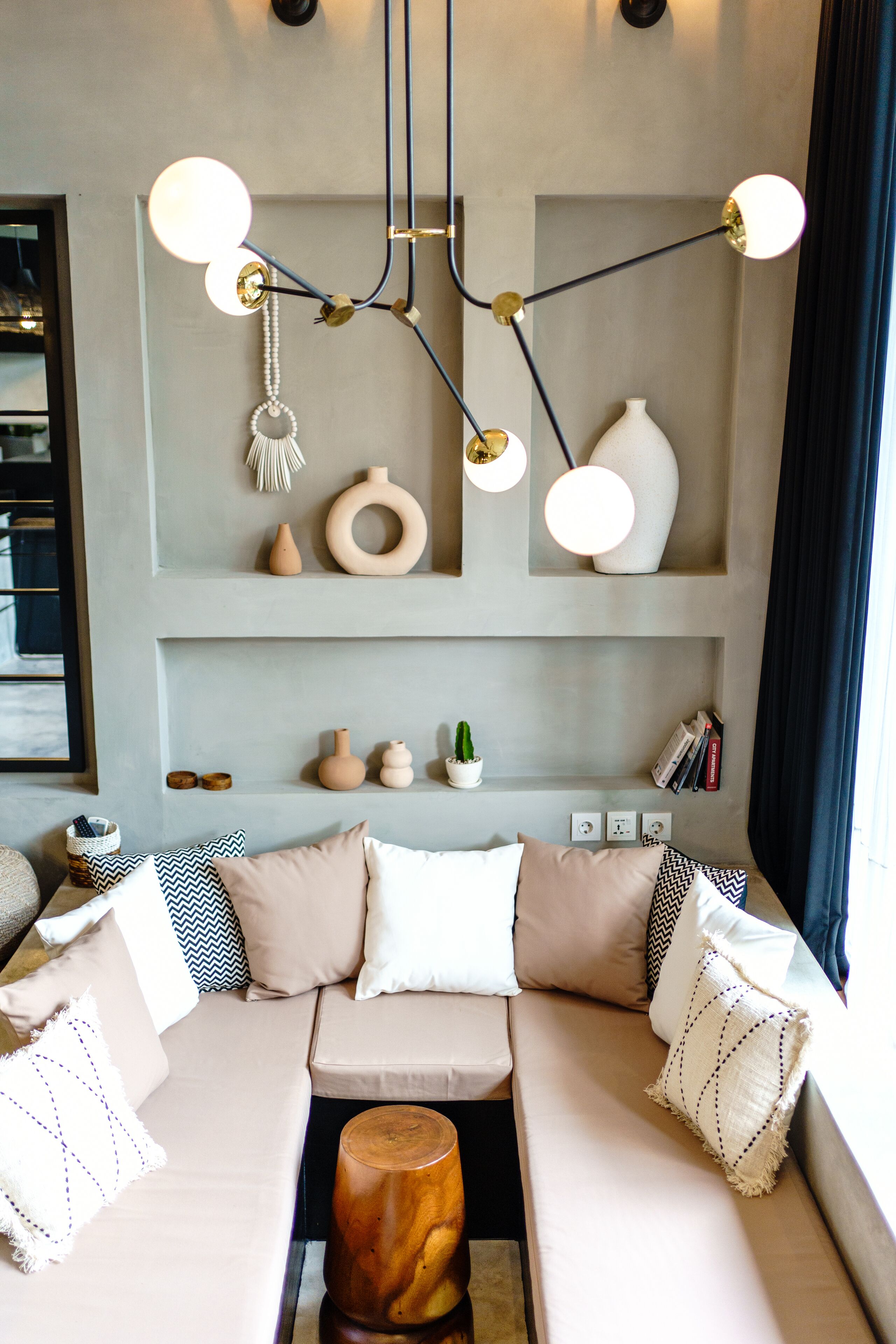 Una sala moderna con un sofá color beige, jarrones decorativos y una lámpara colgante original.