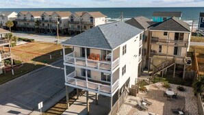 A beachfront property with multiple-story buildings, a balcony with outdoor seating, and a view of the ocean. - Ocean Views + Across from Beach Access! (Surf City)