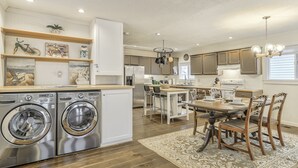 A modern kitchen with built-in appliances, a dining area with wooden chairs, and a large rug. - Ohana Hut (Colorado Springs)