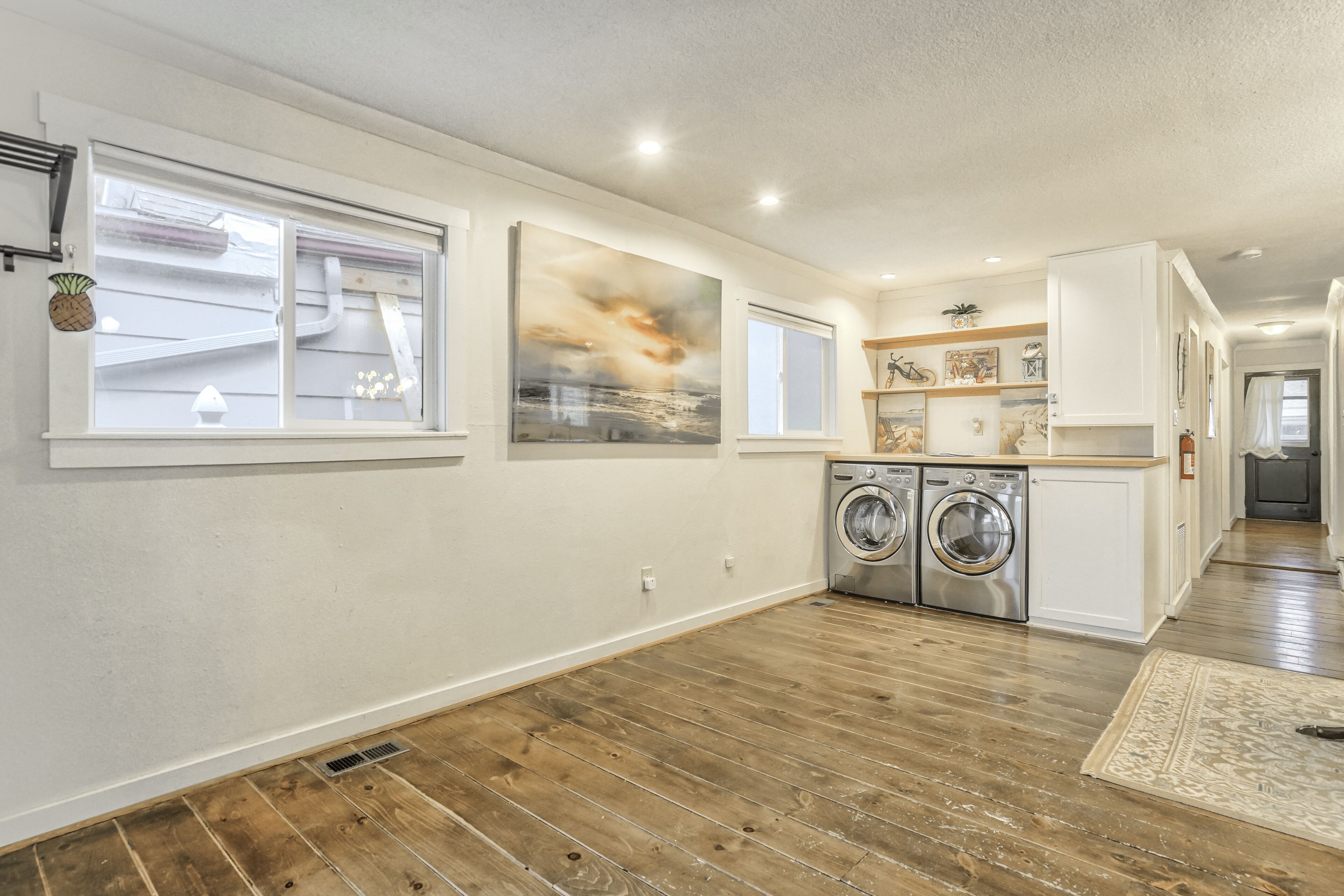 A modern kitchen with wooden flooring, built-in appliances, and a large window.