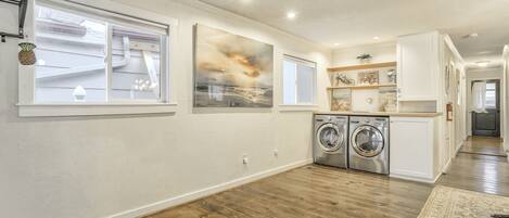 A modern kitchen with wooden flooring, built-in appliances, and a large window.