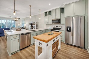 Una cocina moderna con armarios verde claro, electrodomésticos de acero inoxidable y una isla de madera.