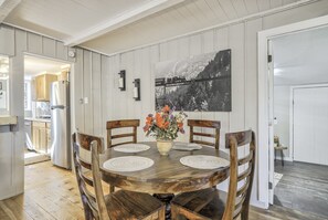 Ein Essbereich mit Holztisch und -stühlen, einer Blumenvase und einem Schwarz-Weiß-Gemälde an der Wand.