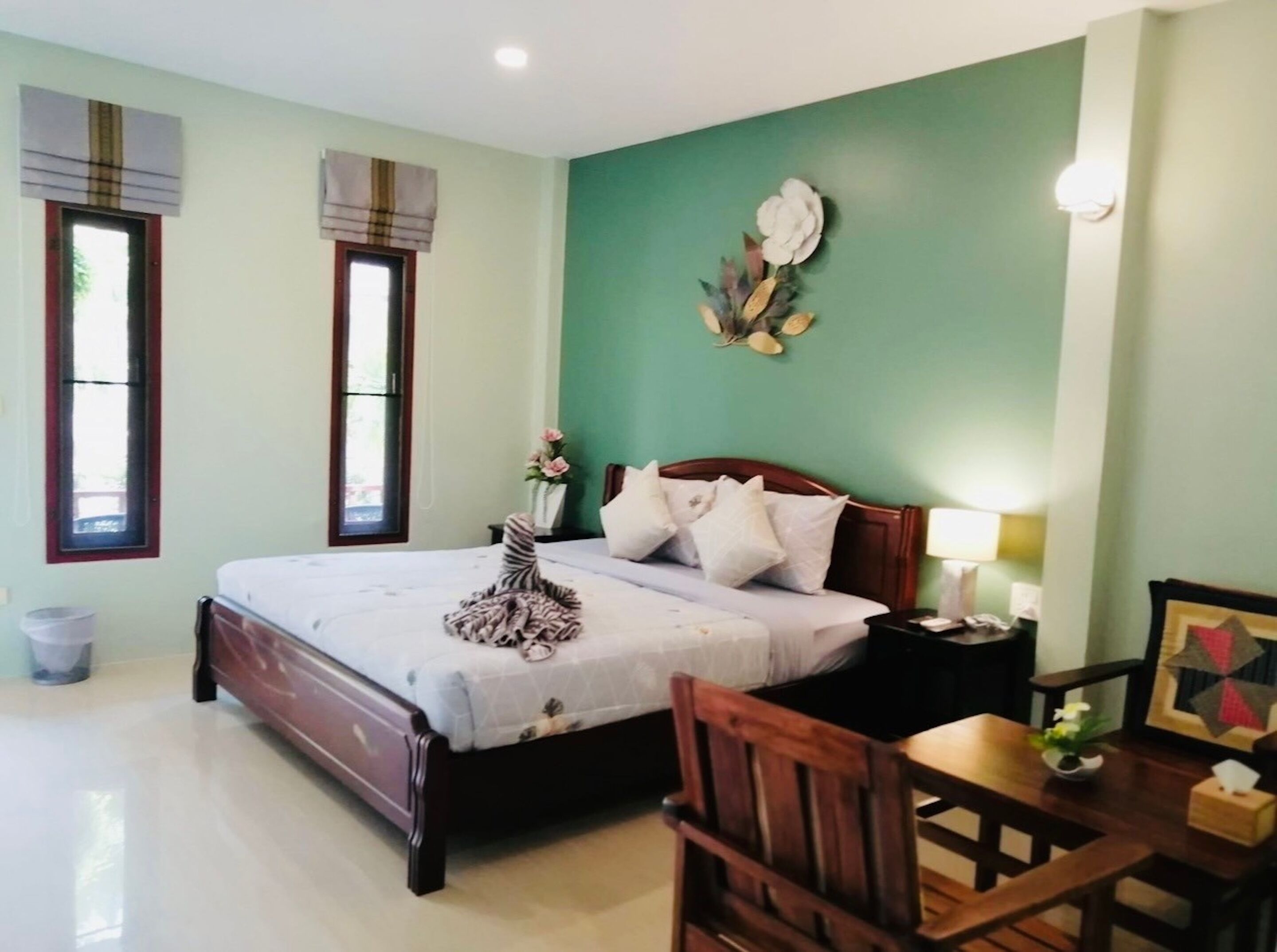A bedroom with a bed, bedside table, chair, and a wall decoration.