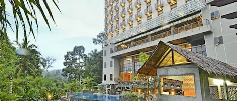 A hotel with a large building, a courtyard with grass and plants, and outdoor seating.