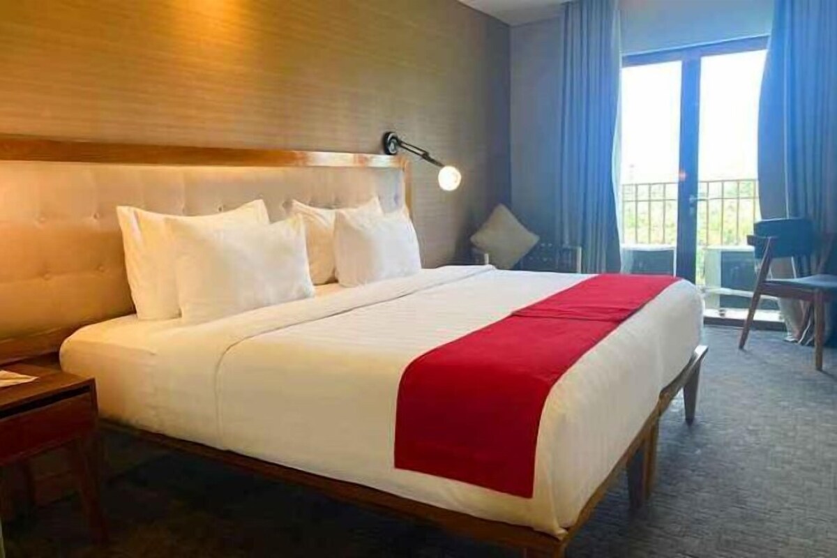 Een hotelkamer met een groot bed, een nachtkastje, een bureau en uitzicht op het landschap.