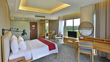 A hotel room with a bed, desk, chair, TV, and a large window offering a view.