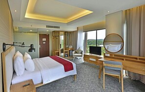 A hotel room with a bed, desk, chair, TV, and a large window offering a view. - FamVida Hotel Lubuklinggau Powered by Archipelago (Lubuklinggau)