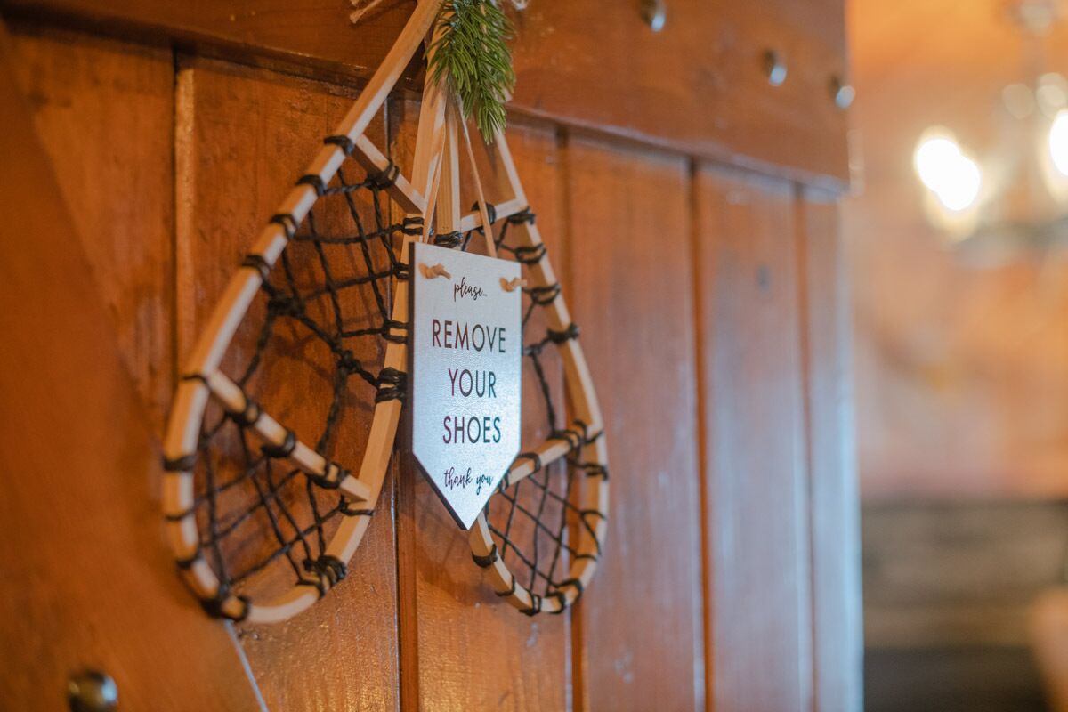 Une porte en bois avec une pancarte indiquant qu’il faut enlever ses chaussures.
