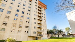 Un immeuble résidentiel à plusieurs étages, doté de balcons, d’un toit plat et d’une pelouse bien entretenue.