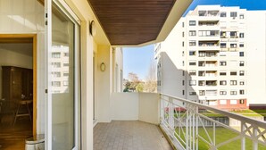 Un balcon doté d’un sol carrelé, d’un plafond en bois et d’une balustrade blanche.