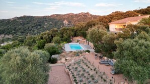 Une villa avec piscine, entourée d’une végétation luxuriante et de collines.