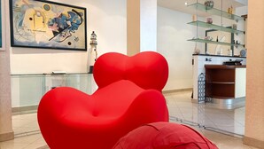 Un intérieur moderne avec une balustrade en verre, un fauteuil rouge en forme de cœur et un tableau accroché au mur.