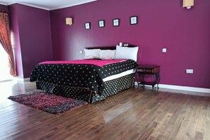 Cozy retreat with a large bed, purple walls, and a wooden floor.